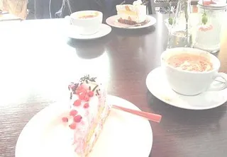 Zwei Kaffeetassen und zwei Stücke Kuchen auf einem Tisch.