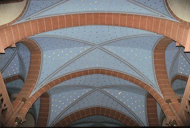Ein blaues Gewölbe mit goldenen Sternen, gerahmt von roten Backsteinbögen.