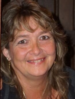 Eine lächelnde Frau mit braunen Haaren und hellbraunen Augen.