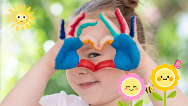 Ein junges Mädchen mit bemalten Händen, die ein Herz formen, und Cartoon-Blumen.