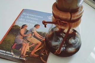 Eine Reisebroschüre und eine Kaffeekaraffe aus Glas auf einem Tisch.