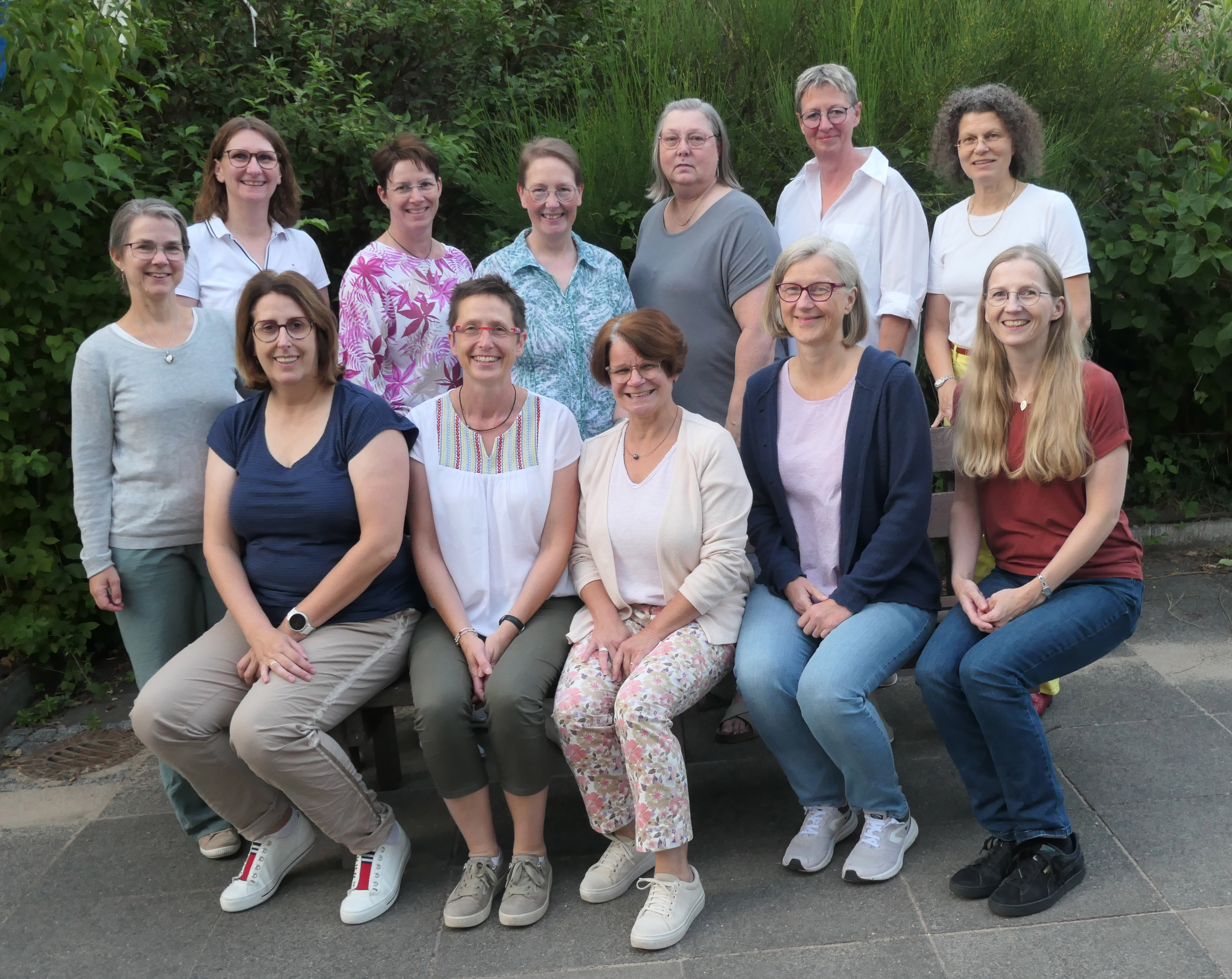 Eine Gruppe von zwölf lächelnden Frauen posiert für ein Foto im Freien.